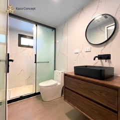 Salle de bain du KAZ Pavillon : douche vitrée, WC et vasque noire sur meuble bois, murs effet marbre